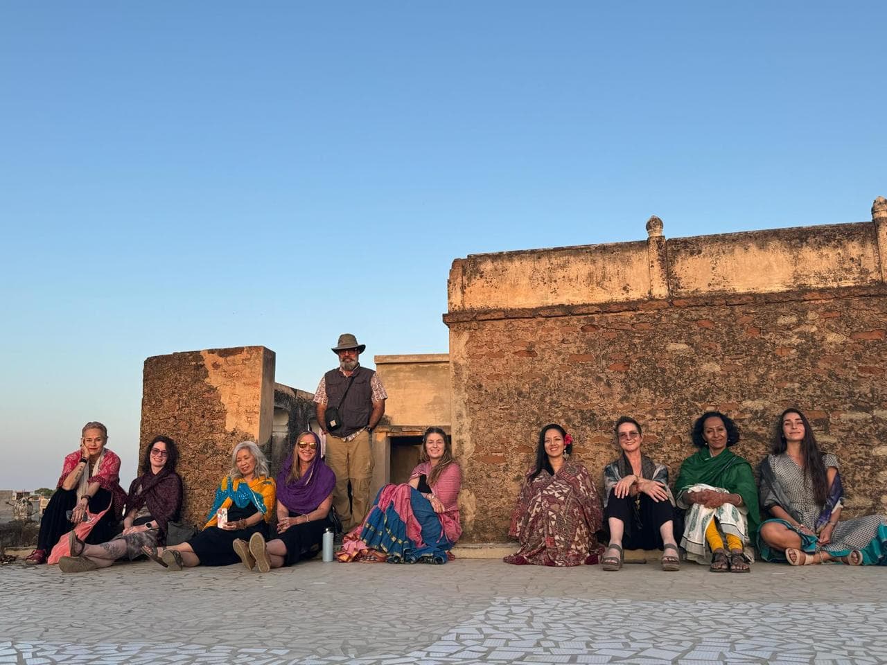 Travellers resting along a fort wall in the evening light