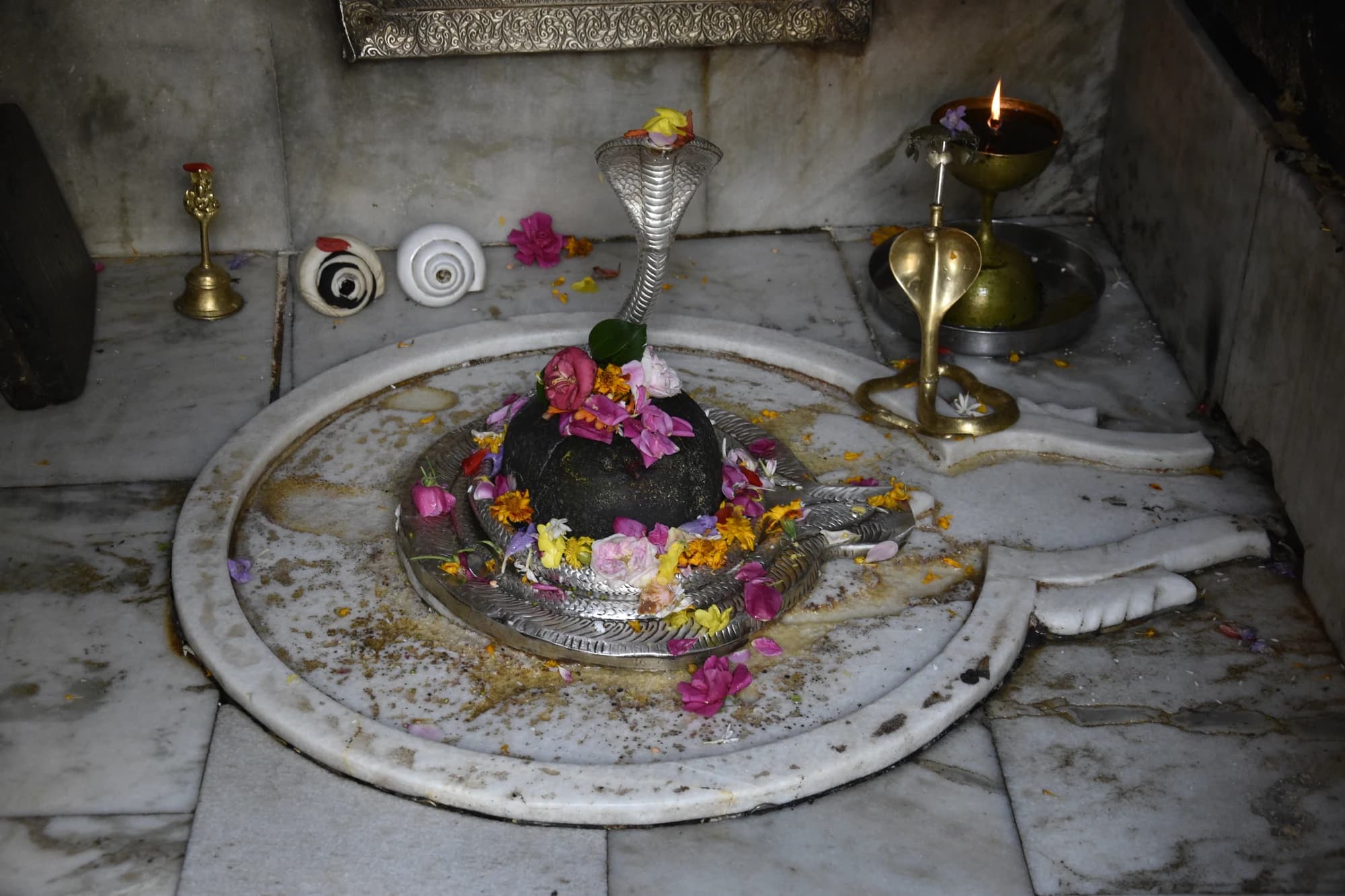 A lingam with flowers and oil lamps