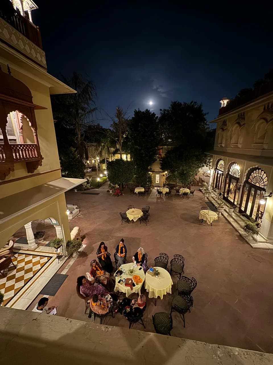 Guests gathered at tables in a heritage hotel courtyard at night